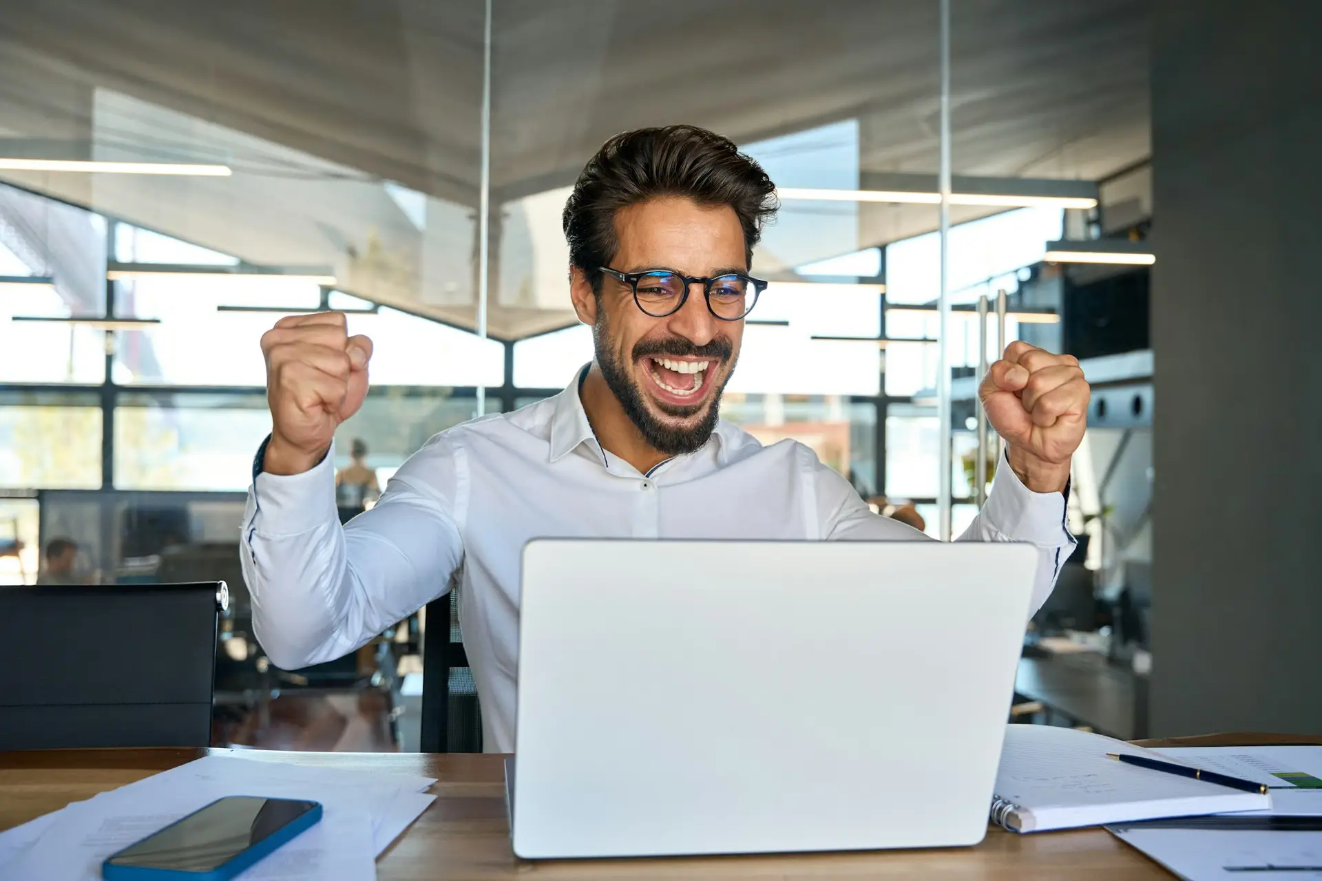 Happy business man celebrating professional achievement in office.